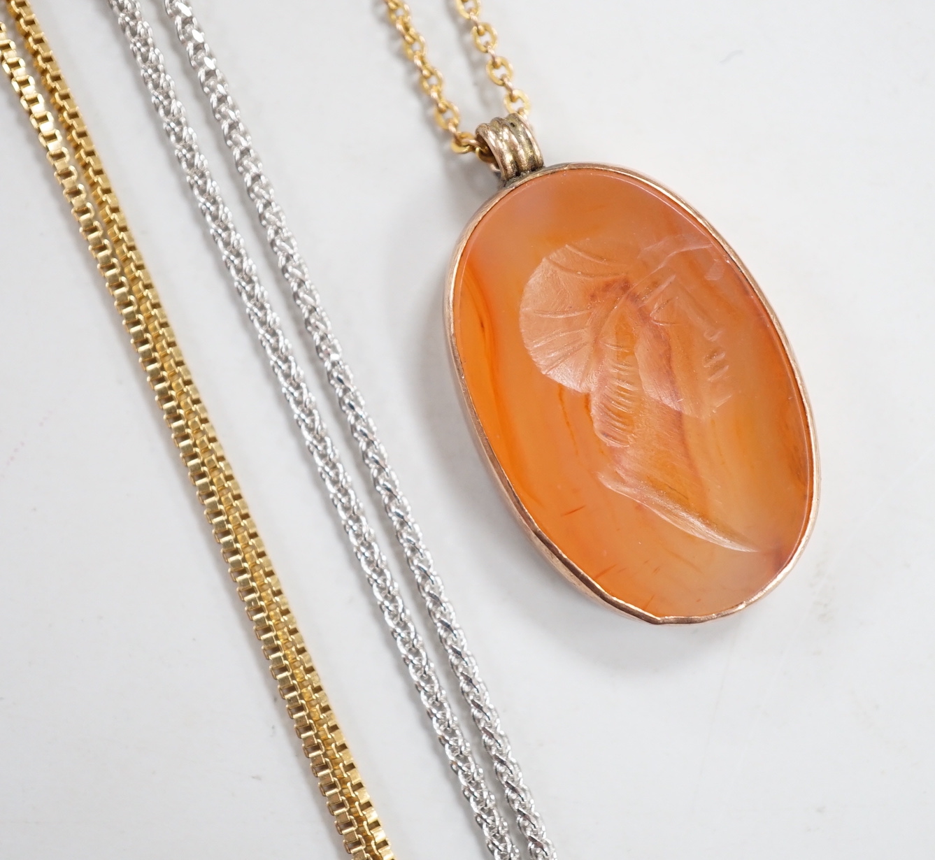 A yellow metal mounted oval intaglio carnelian stone, carved with the bust of gentleman to sinister, 23mm on a 9ct fine link, 37cm and two 9ct gold chains. including white gold, gross weight 8.7 grams.